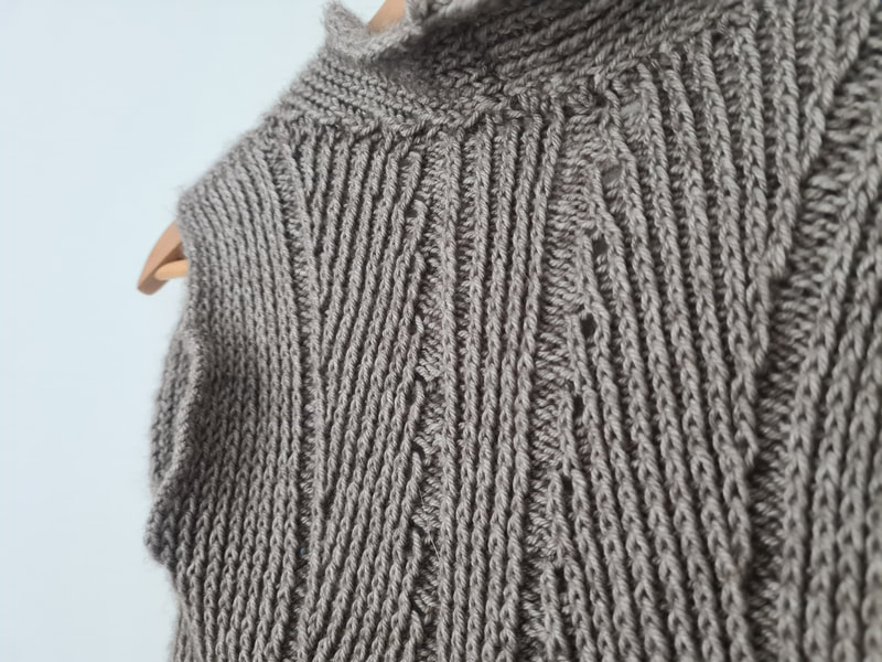 Close up of twisted ribbing and lace on the back of a handknitted cardigan